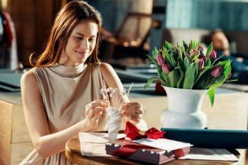 Krásná žena s tulipány, dárkovým balíčkem a stříbrnými květinami ve váze, originální dárek k narozeninám