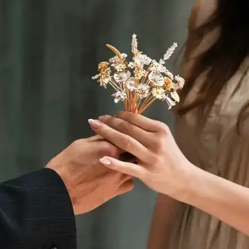 Woman receiving gifted gold flowers from a man, gift for her