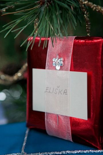 Stříbrná květina zdobí zabalený vánoční dárek