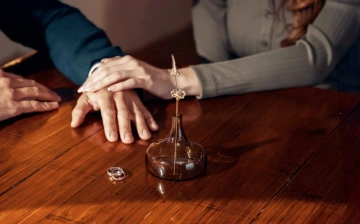 Hands of a woman and man with wedding rings and two golden flowers in a glass vase, alternative wedding rings