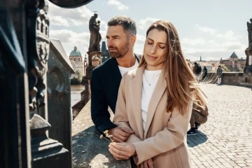 Muž a žena držící zlaté květiny na Karlově mostě v Praze