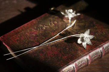 Dva narcisy ze stříbra položené na deníku