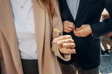 Dvě zlaté květiny v ruce manželky a vedle stojící manžel, dárek k výročí svatby