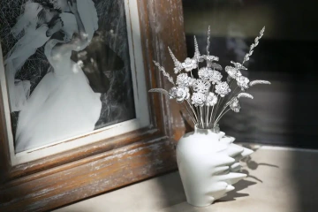A vase with large golden bouqet of flowers in front of wedding picture