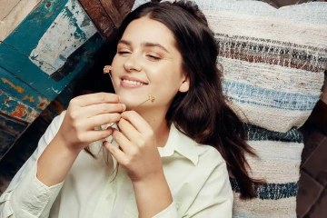 Mladá žena se směje na dvě šperkařské květiny, které drží v ruce, pravidelné darování květin