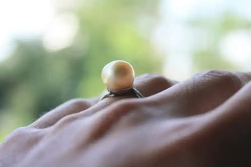 Prst ženy s prstýnkem s perlou