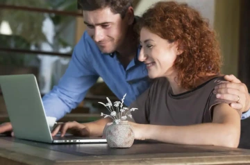 Working woman and man with corporate gift, vase of silver flowers on table