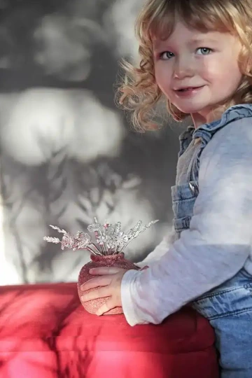 Baby girl holding vase with silver flowers, the gift for mom from daughter