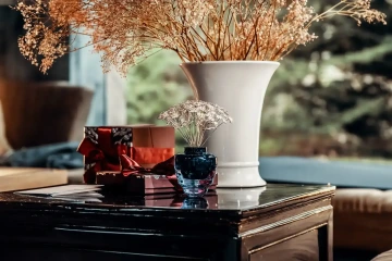 Stříbrné květinové šperky GIYOU v modré váze na stolku s dárkovými balíčky