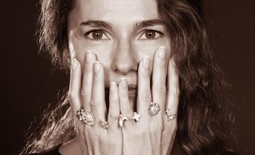 Žena se stříbrnými květinovými šperky mezi prsty. Květiny pro postupné sbírání.