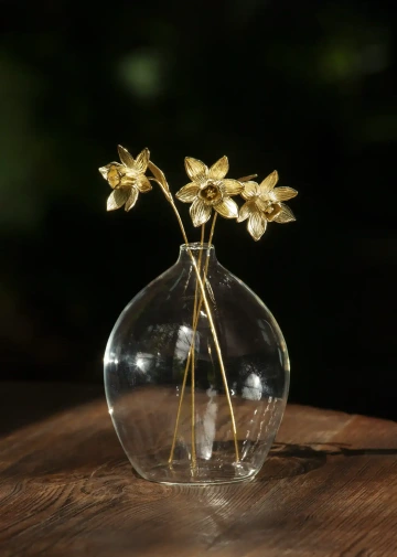 Three golden daffodils in a glass vase for luxury decoration