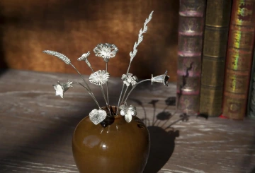 Stříbrné květiny GIYOU v hnědé váze, v knihovně.