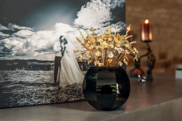 Large bouquet of golden flowers in a black vase on a red chest of drawers, luxurious wedding bouquet