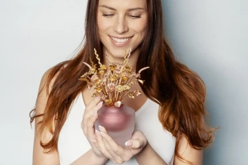 Velká kytice zlatých květin v rukách krásné ženy, luxusní dárek pro ženu