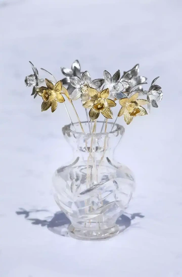 Kytice květinových šperků, stříbrných a zlatých narcisů ve váze