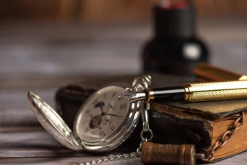 Old watch with pen and notebook on table, meaningful gifts