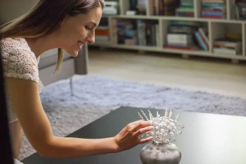 Smějící se krásná žena rovnající stříbrné květiny ve váze