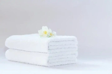 Poskládané bílé ručníky s položenými květy, dárek manželce k narození dítěte