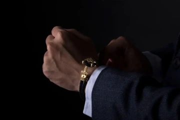 Ruka muže zapínající si luxusní náramek pro muže