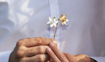 Svatebčané drží v ruce dva zlaté narcisy jako netradiční snubními prsteny pro svatební obřad