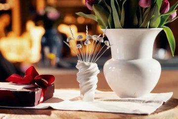 Na stole položenéa váza se šperkařskou kyticí, váza s tulipány a dárková krabička pro originální dárek pro ženu k narozeninám