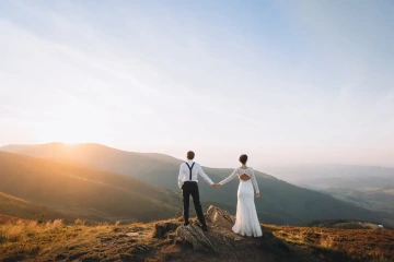 Ženich a nevěsta na horách se drží za ruku. Originální svatba