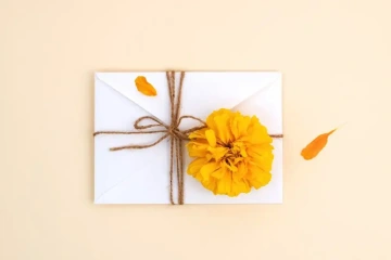 Zabalená obálka s penězi a žlutou květinou, dárek k promoci