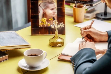 Váze se šperkařskými květinami na pracovním stole s mužem a fotkou ženy