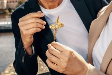 Ruce ženy a muže s květinami ze zlata