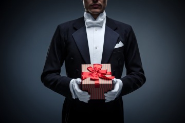Man in tuxedo and white gloves with perfect luxury gift