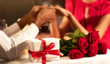 Valentýnský stůl s mužem a ženou a s růžemi, azabaleným dárkem k Valentýnu