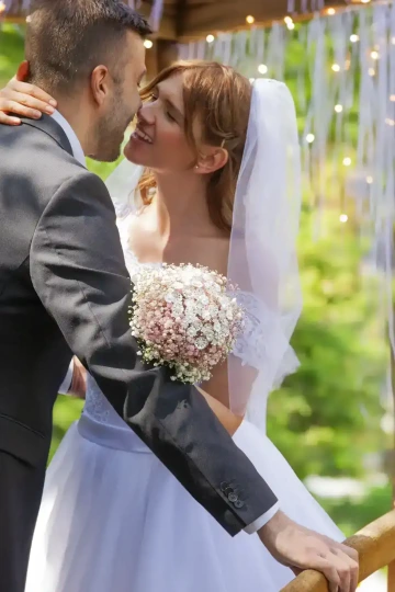 Ženich a nevěsta se líbají a drží svatební kytici ze stříbra