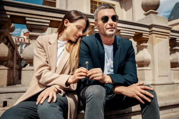 Man and woman siting on Old Towm Square in Prague with unique souvenir from Prague