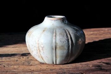 An old ceramic vase for GIYOU flowers on a wooden table.