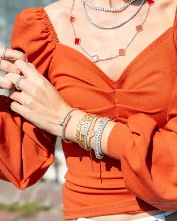 Ruce ženy s více náramky a prstýnky na rukách