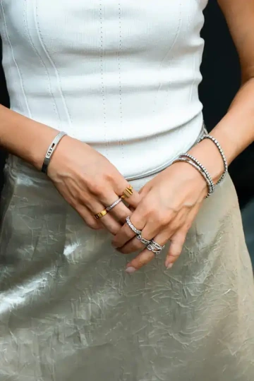 Ruce elegantní ženy s více náramky a prstýnky