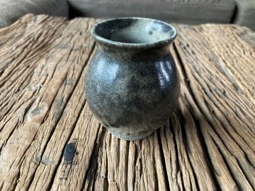 Dark ceramic vase on a wooden table.