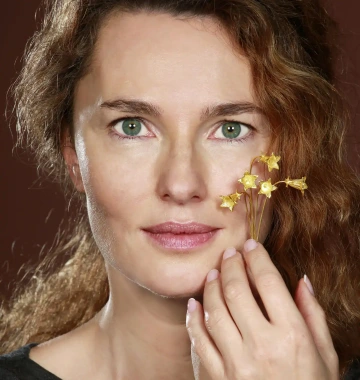 Woman holding in her hand a beautiful gift of golden flowers as a gift for her