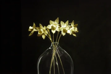 Golden flowers daffodils in a glass vase as alternative wedding rings for luxury wedding